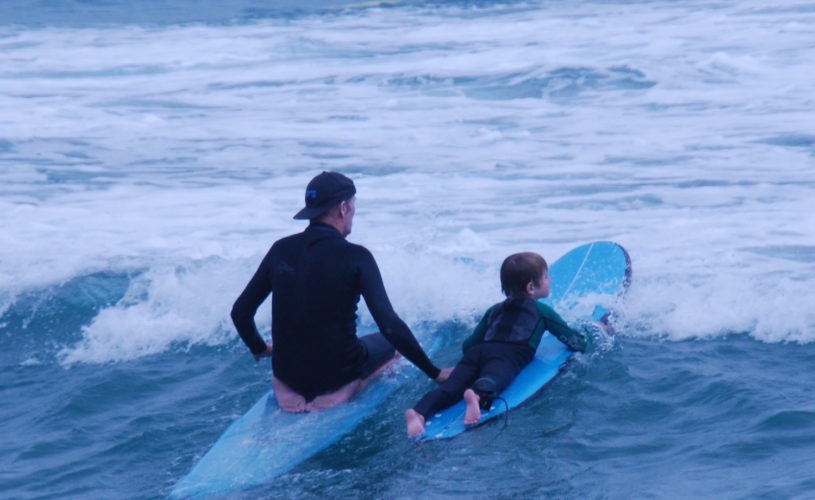 Rusty Miller teaching a young boy to surf at Byron Bay
